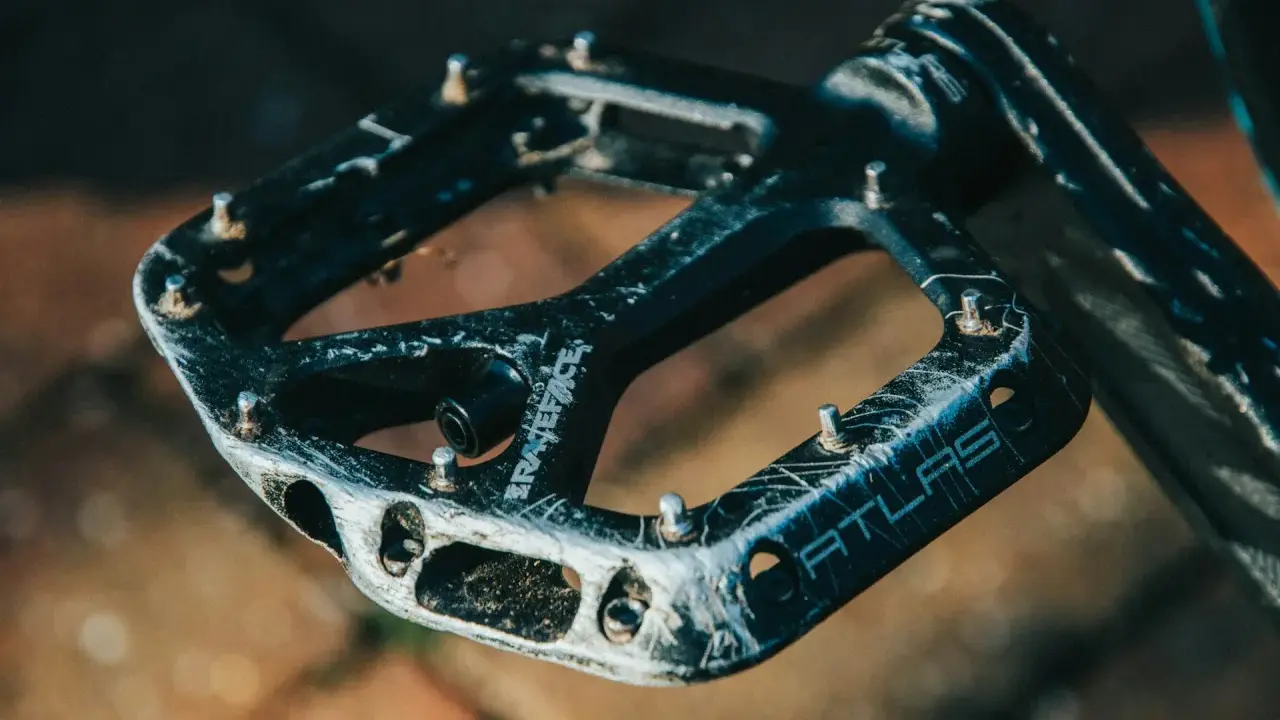 Czarne pedały Race Face Atlas, idealne jakie pedały do MTB, z widocznymi śladami użytkowania i pinami.