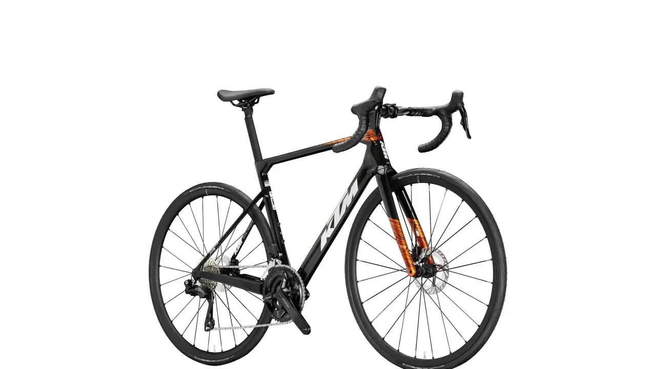 Czarny rower szosowy KTM Revelator Alto z pomarańczowymi akcentami, gotowy na podbój szos.