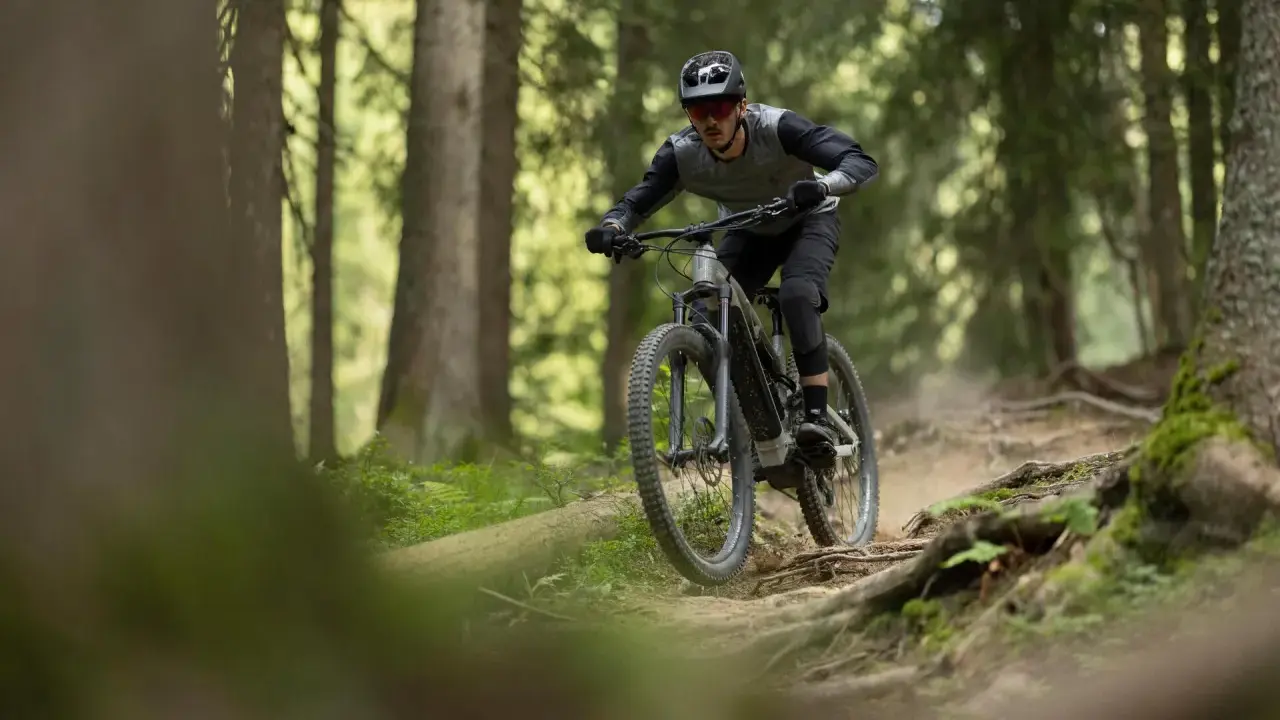 Rowerzysta w kasku i okularach zjeżdża po wyboistej leśnej ścieżce. To właśnie jest **co to enduro** – jazda po trudnym terenie.