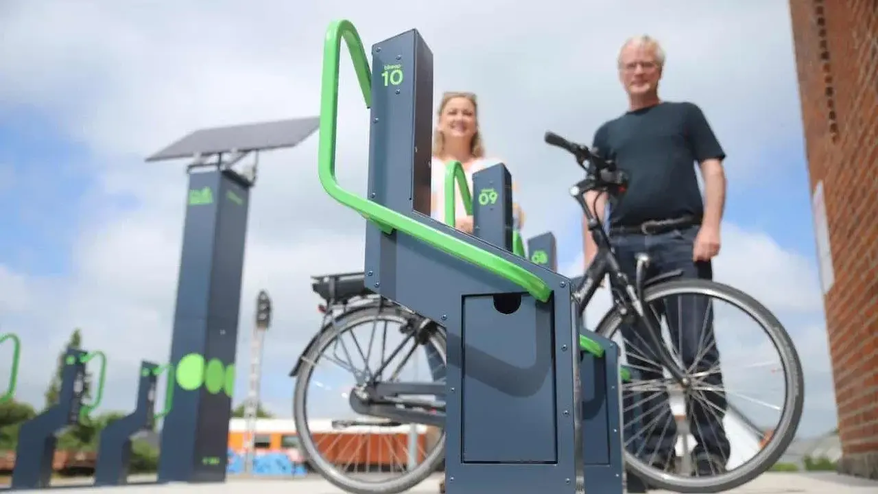 Stacja ładowania rowerów elektrycznych zasilana energią słoneczną. Para ludzi korzysta z nowoczesnych stojaków.