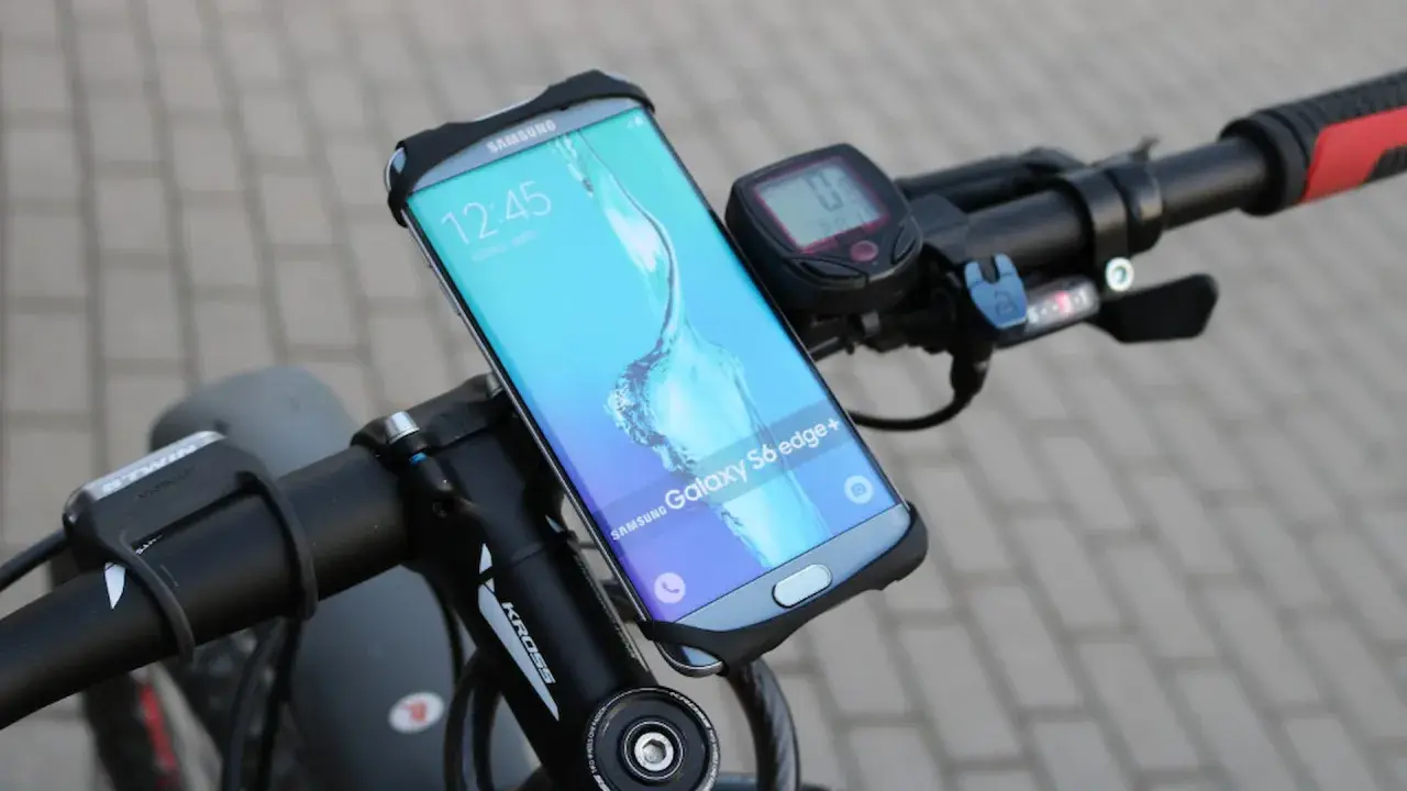 Jaki uchwyt na telefon do roweru? Samsung Galaxy S6 edge+ zamontowany na kierownicy roweru, obok licznika.
