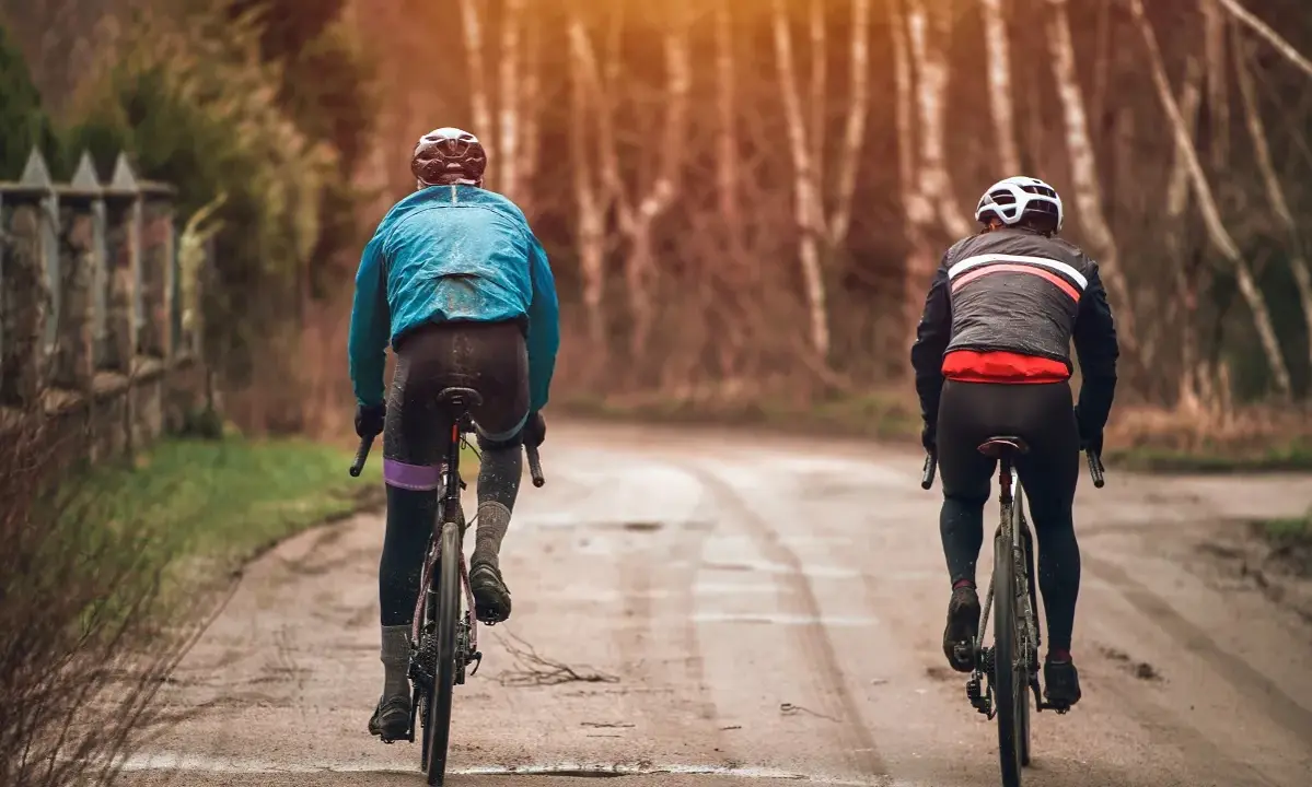 Dwóch rowerzystów w jesiennych strojach, idealnych na 15 stopni. Lekkie kurtki i długie spodnie zapewniają komfort podczas jazdy.