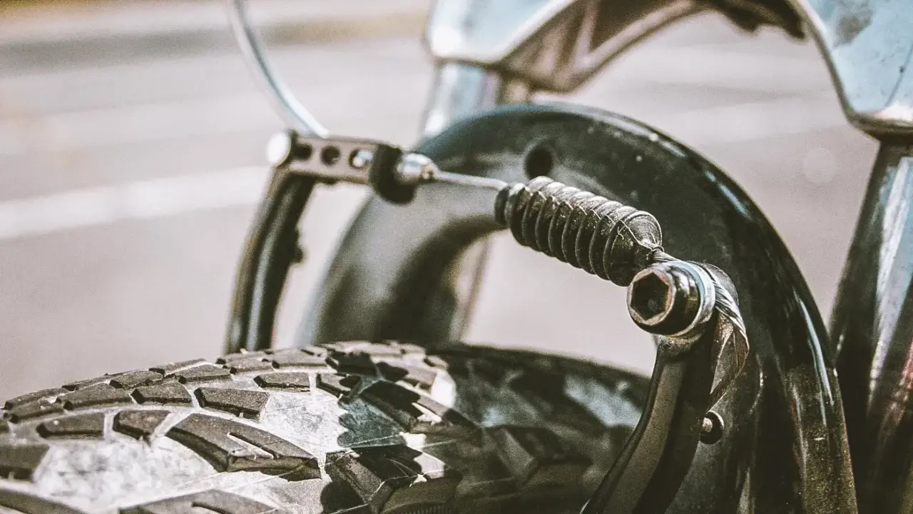 Zbliżenie na mechanizm hamulca rowerowego z widoczną sprężyną i linką. Dowiedz się, jak poluzować hamulce w rowerze.