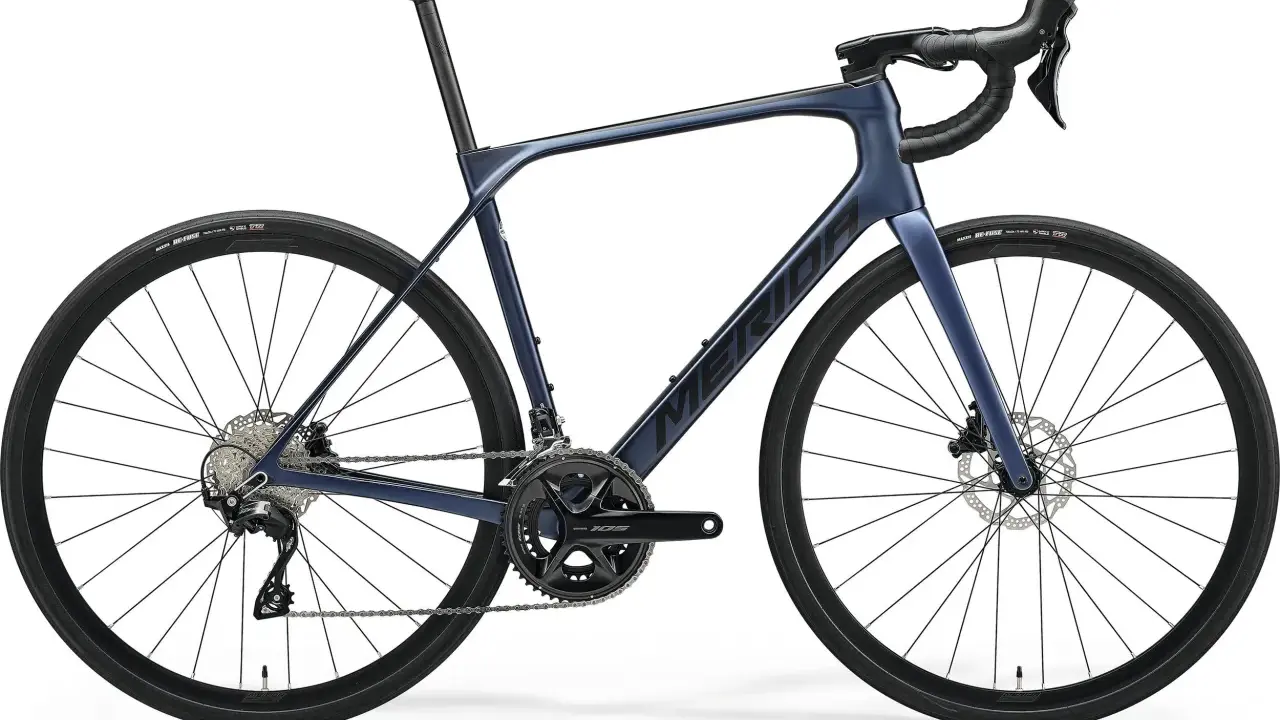 Granatowy rower szosowy endurance z hamulcami tarczowymi i napędem Shimano 105. Idealny na długie trasy.