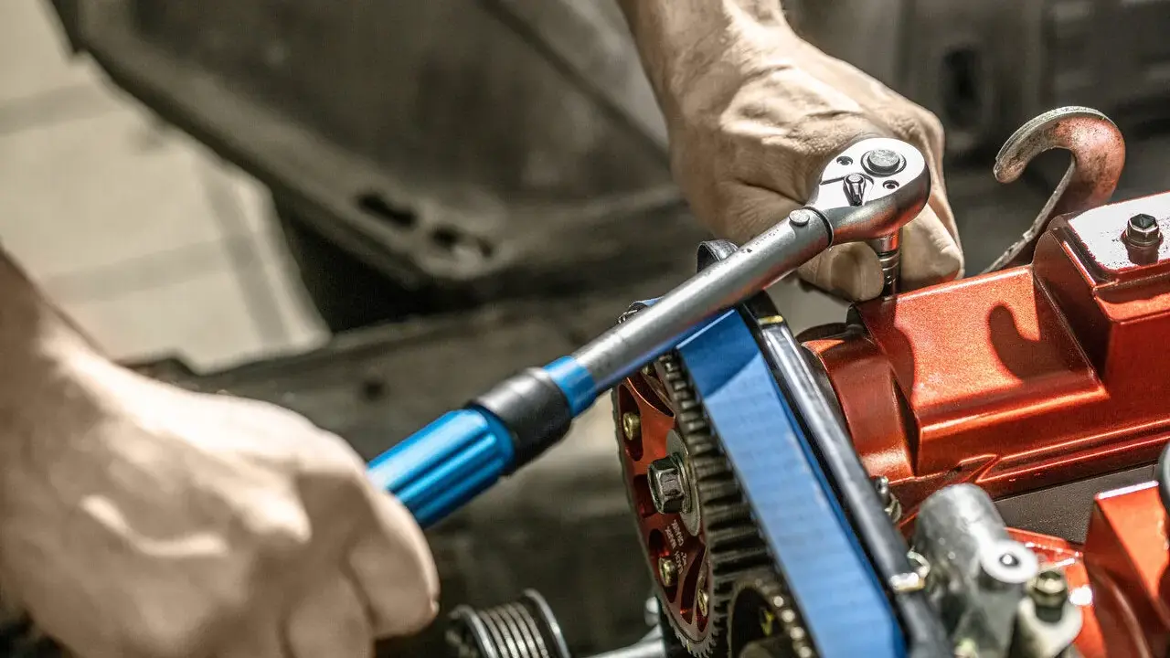 Mechanik używa klucza dynamometrycznego do precyzyjnego dokręcania śrub w silniku. To narzędzie jest kluczowe, by wiedzieć, klucz dynamometryczny co to i jak go używać.