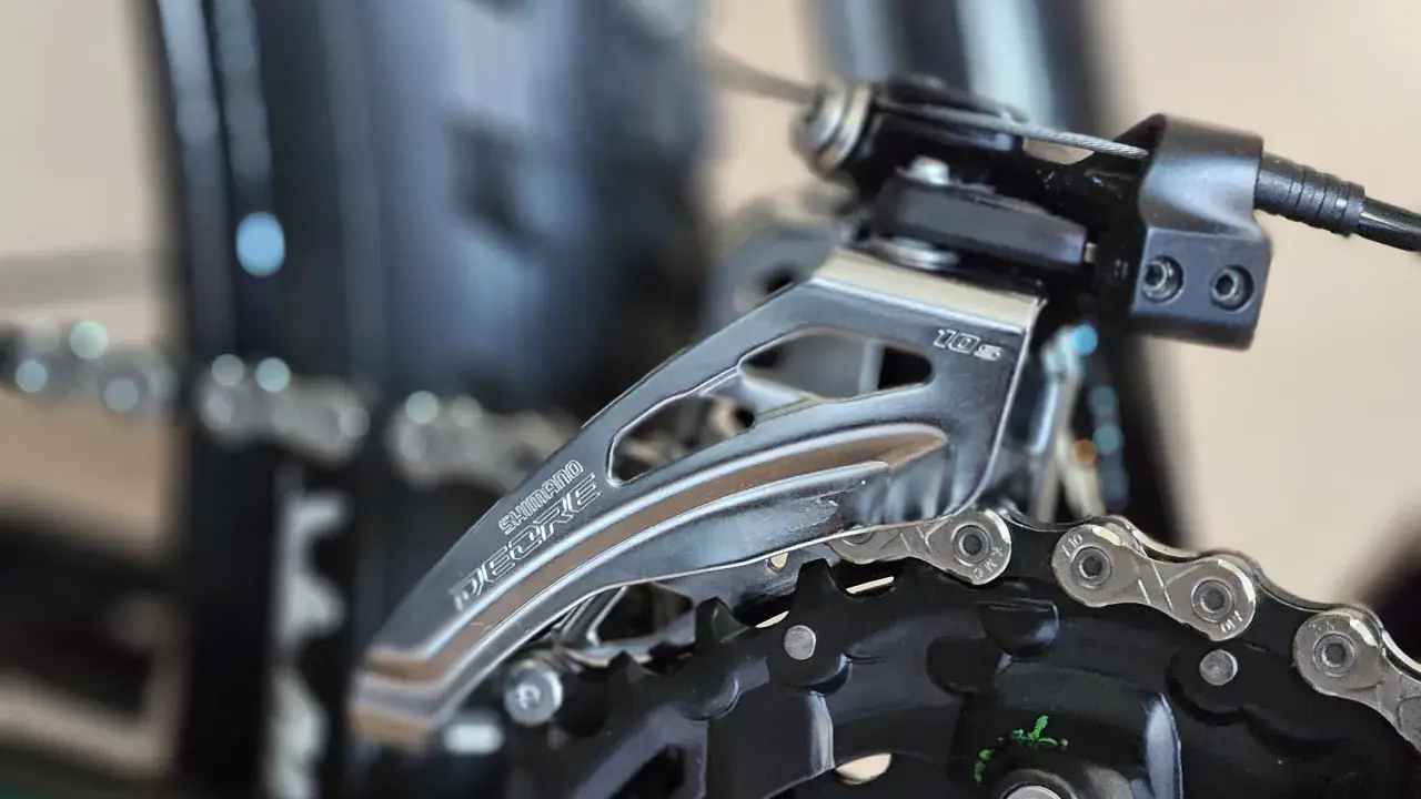 Zbliżenie na przednią przerzutkę rowerową Shimano Deore. Dowiedz się, jak zmieniać przerzutki w rowerze, by jazda była płynniejsza.