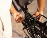 Ręce zaciskają blokadę roweru na ramie, zabezpieczając go przed kradzieżą.