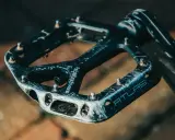 Czarne pedały Race Face Atlas, idealne jakie pedały do MTB, z widocznymi śladami użytkowania i pinami.