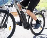 Mężczyzna pedałuje na rowerze elektrycznym, pokazując, jak działa rower elektryczny. Bateria i silnik są widoczne na ramie.