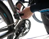 Dłoń reguluje przerzutkę tylną Shimano Tourney, dbając o płynną zmianę biegów w rowerze.