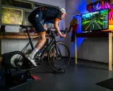 Intensywny trening na trenażerze kolarskim w wirtualnym świecie. Kolarz w stroju sportowym pedałuje, śledząc trasę na ekranie.