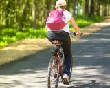 Osoba na rowerze w lesie. Zastanawiasz się, ile jeździć na rowerze, żeby schudnąć? Długie trasy pomogą Ci osiągnąć cel.