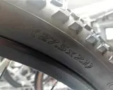 Na oponie rowerowej widoczny napis (27.5x2.1), który pomaga określić, jak zmierzyć rozmiar koła w rowerze.