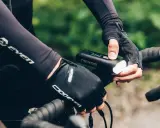 Rowerzysta w rękawiczkach sprawdza mocne oświetlenie rowerowe STREAK1000. Dobre oświetlenie to podstawa bezpieczeństwa.