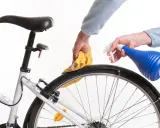 Czyszczenie piasty roweru. Ręce z żółtą ściereczką i niebieskim spryskiwaczem dbają o rower.
