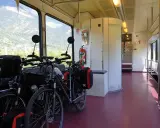 Dwa rowery z sakwami czekają na podróż. Widać okno z widokiem na góry. To praktyczny sposób, jak powiesić rower w pociągu.