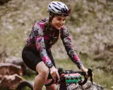 Uśmiechnięta rowerzystka w kwiecistej bluzie pokonuje kolejne kilometry. 100 km na rowerze to wyzwanie, ale radość z jazdy jest widoczna.