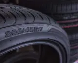 Zbliżenie na oponę z widocznymi oznaczeniami 205/45R17. W tle widać stos innych opon.