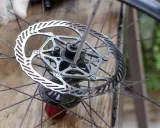 Rękawiczka i śrubokręt przy tarczy hamulcowej roweru. Czyszczenie tarcz hamulcowych to ważny element dbania o rower.