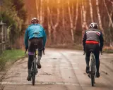 Dwóch rowerzystów w jesiennych strojach, idealnych na 15 stopni. Lekkie kurtki i długie spodnie zapewniają komfort podczas jazdy.