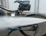 Czyszczenie roweru na myjni. Silny strumień wody spłukuje brud z opon i ramy.