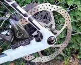 Regulacja hamulca tarczowego mechanicznego w rowerze. Widoczny zacisk TRP, tarcza hamulcowa i fragment ramy.