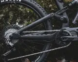 Część roweru elektrycznego z napędem **Shimano EP8** w deszczu. Widoczna kaseta, przerzutka, łańcuch i korba.