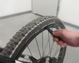 Dłoń używa łyżki do opon do wymiany opony w rowerze.