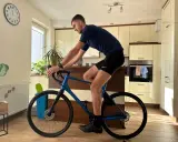 Mężczyzna w stroju kolarskim ćwiczy na rowerze gravel w domu. Poprawna pozycja na rowerze gravel jest kluczowa dla komfortu i wydajności.