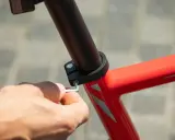 Dłoń dokręca śrubę imbusową mocującą sztycę rowerową. Różne sztyca rowerowa rozmiary są dostępne, aby dopasować się do każdej ramy.