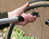 Dłoń z pompką przykłada się do wentyla, by sprawdzić, ile powietrza w rowerze.