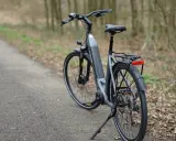 Szary rower elektryczny na ścieżce w lesie. Kto wynalazł rower? Dziś mamy ich wiele, ale początki były skromne.
