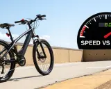 Czarny rower elektryczny na tle nieba i drogi. Obok prędkościomierz z napisem "SPEED VS RANGE", sugerujący maksymalna prędkość roweru elektrycznego.