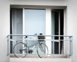 Stylowy rower z wiklinowym koszykiem czeka na balkonie na kolejną przejażdżkę.