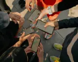 Grupa biegaczy analizuje swoje wyniki na telefonach. Widoczne ekrany aplikacji Strava po polsku pokazują mapy tras i statystyki.