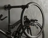 Czarny rower wiszący na ścianie na industrialnym wieszaku. Prosty sposób, jak powiesić rower na ścianie, oszczędzając miejsce.