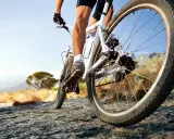 Kolarz na rowerze crossowym lub trekkingowym pokonuje kamienistą ścieżkę w słoneczny dzień.