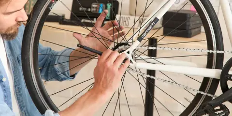 Mężczyzna próbuje zdjąć zębatkę z tylnego koła roweru, używając narzędzia.