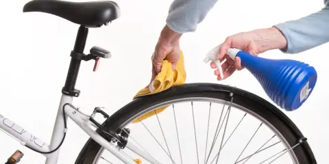 Czyszczenie piasty roweru. Ręce z żółtą ściereczką i niebieskim spryskiwaczem dbają o rower.