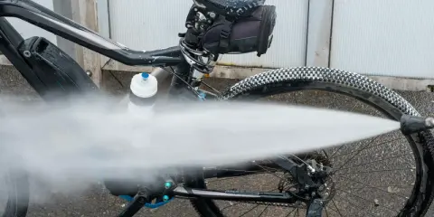 Czyszczenie roweru na myjni. Silny strumień wody spłukuje brud z opon i ramy.
