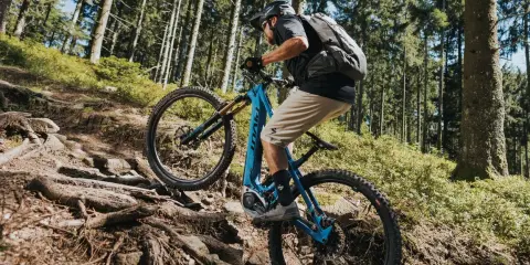 Kolarz na rowerze elektrycznym z napędem Bosch Performance Line CX pokonuje kamienisty, leśny szlak.