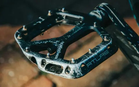 Czarne pedały Race Face Atlas, idealne jakie pedały do MTB, z widocznymi śladami użytkowania i pinami.