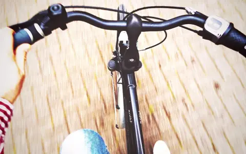 Widok z perspektywy rowerzysty. Dłoń trzyma kierownicę, a przed nami rozmyte tło. Jak podnieść kierownicę w rowerze?