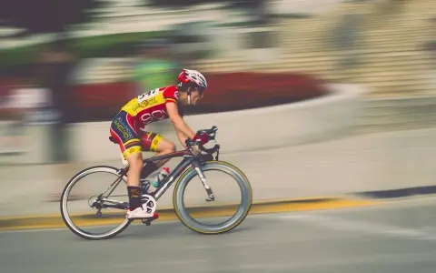 Kolarz w żółto-czerwonym stroju pędzi na rowerze podczas maratonu rowerowego.