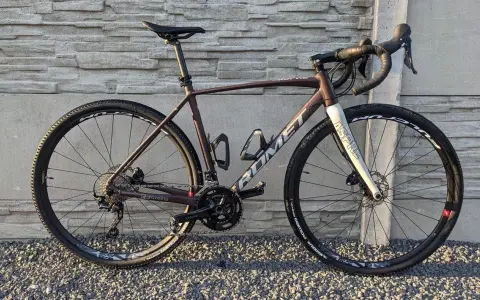 Brązowy rower gravelowy Romet Aspre 2 z białym widelcem, gotowy na przygodę po szutrowych drogach.