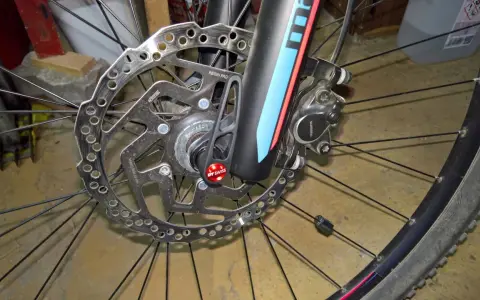 Hamulec tarczowy roweru z mocowaniem **center lock**. Widoczna tarcza hamulcowa Shimano, zacisk i szybkozamykacz DT Swiss.