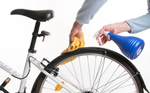 Czyszczenie piasty roweru. Ręce z żółtą ściereczką i niebieskim spryskiwaczem dbają o rower.