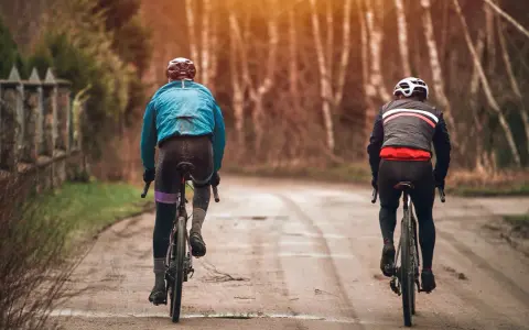 Dwóch rowerzystów w jesiennych strojach, idealnych na 15 stopni. Lekkie kurtki i długie spodnie zapewniają komfort podczas jazdy.