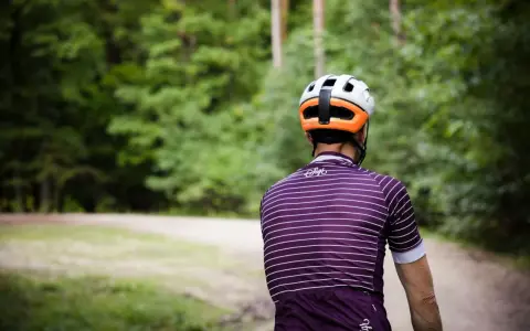 Kolarz w kasku i koszulce w paski jedzie ścieżką przez las. Idealny rower crossowy na takie wyprawy.