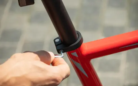 Dłoń dokręca śrubę imbusową mocującą sztycę rowerową. Różne sztyca rowerowa rozmiary są dostępne, aby dopasować się do każdej ramy.